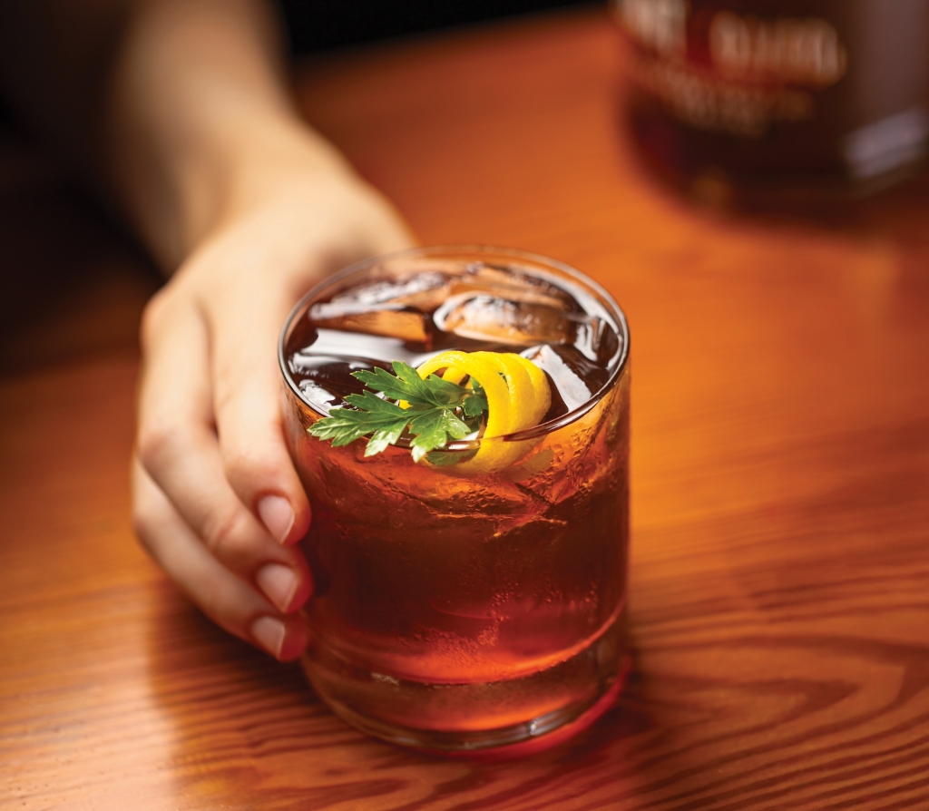 A hand presenting an elegant brown liquor cocktail