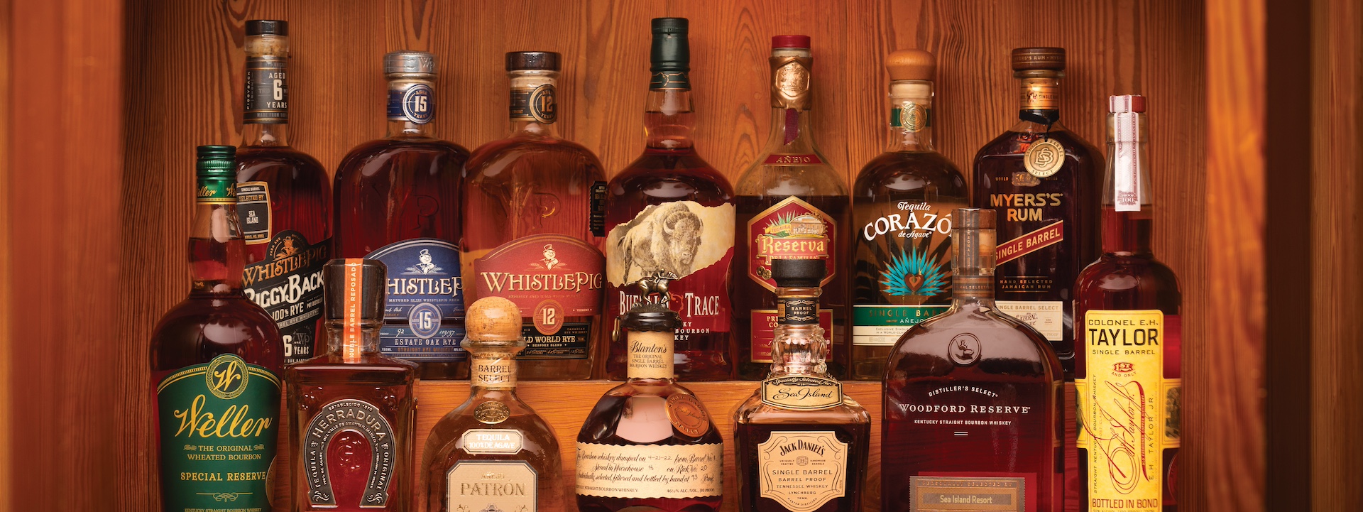 Two rows of brown liquors on a bar shelf