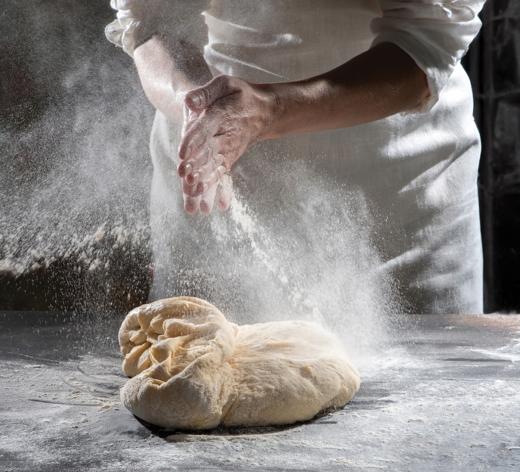 Beautiful moment of unknown woman in white linen apron preparing dough pastry with white flour