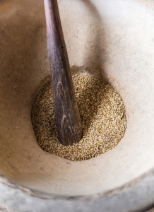 Big traditional stone mortar with fresh corn and wooden pestle