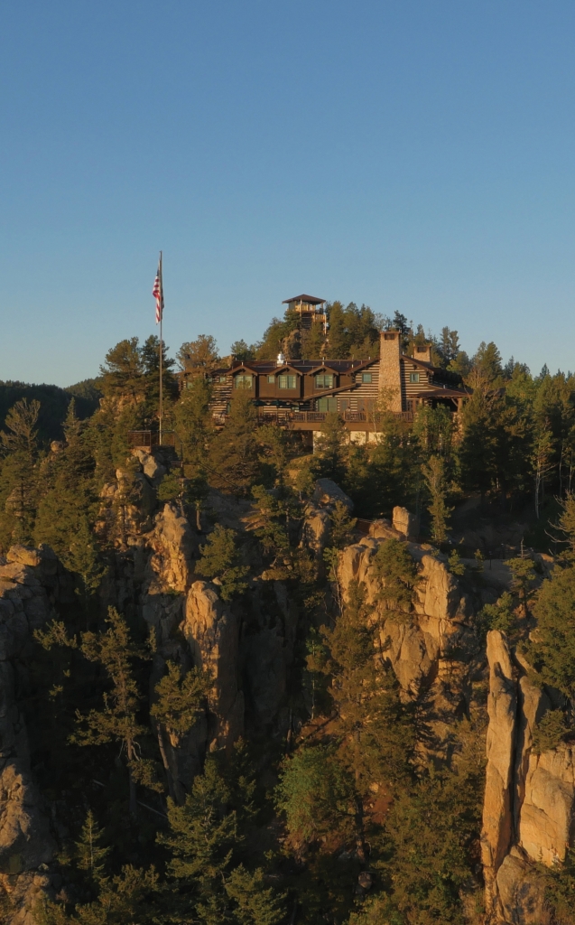 A cottage perched at the top of a tree-lined ridge