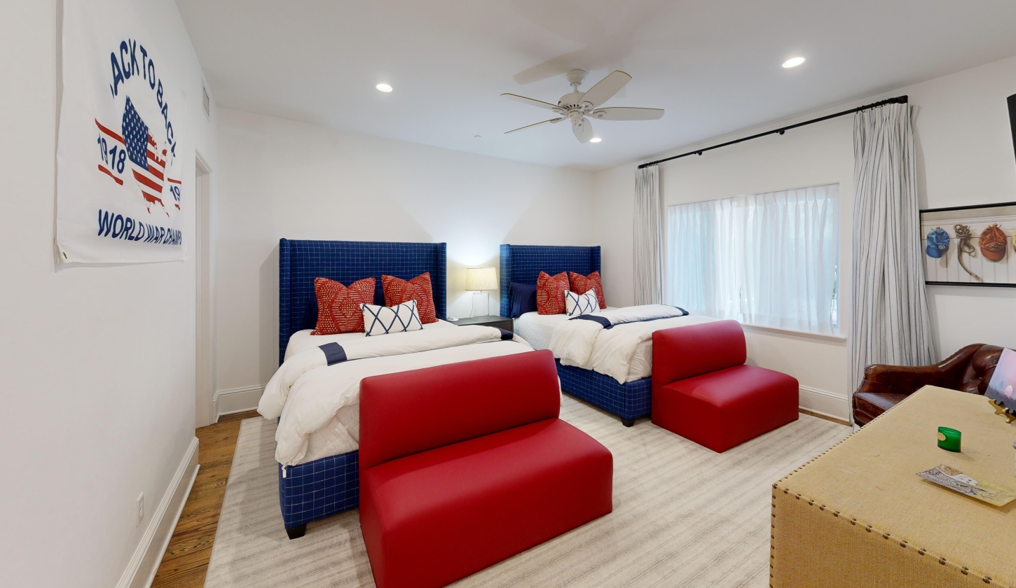 A bedroom with two queen beds designed in white, blue, and red.