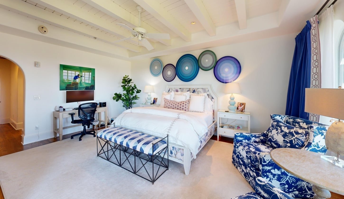 A large bedroom with a king bed at its center and a desk to the left