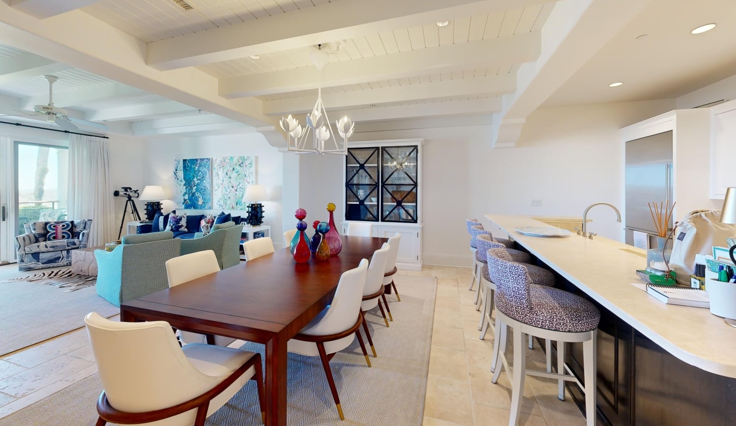 A long wooden dining table sits next to a kitchen island
