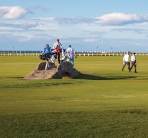 Golfers and caddies crossing Swilcan Bridge at the Old Course at St Andrews.