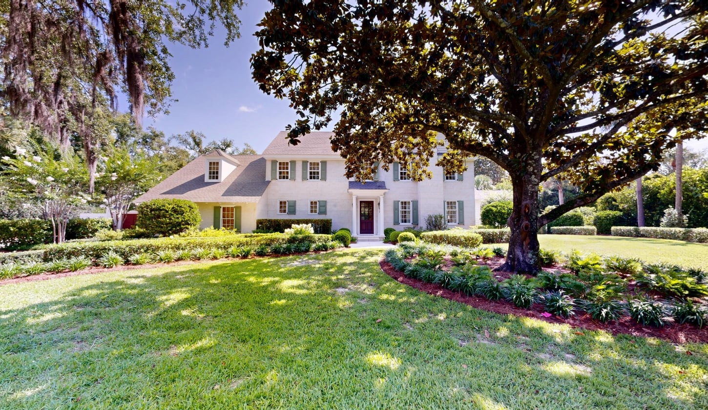A green lawn with trees and a large white cottage