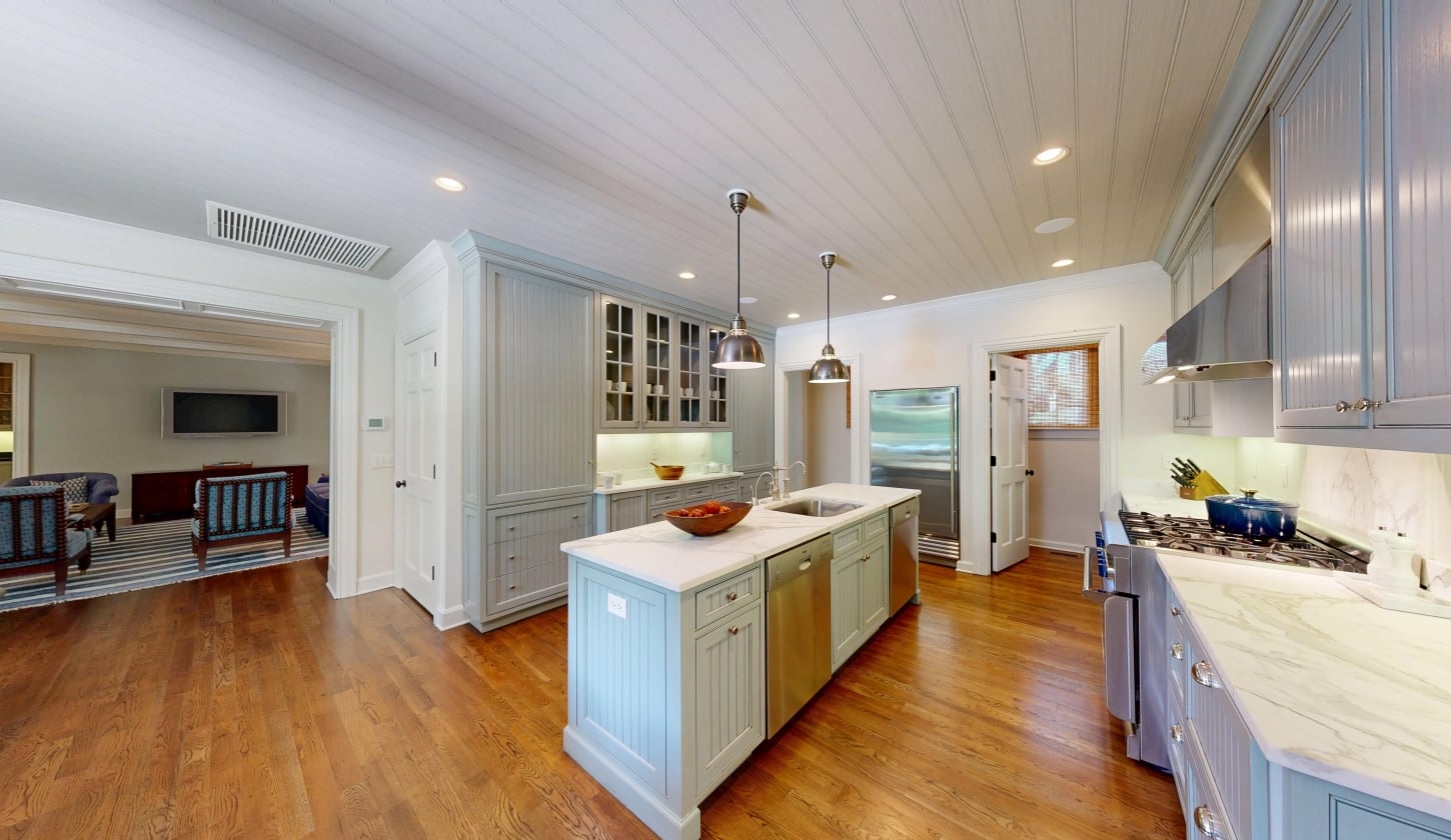 A kitchen with wood floors, white cabinetry, and a large island