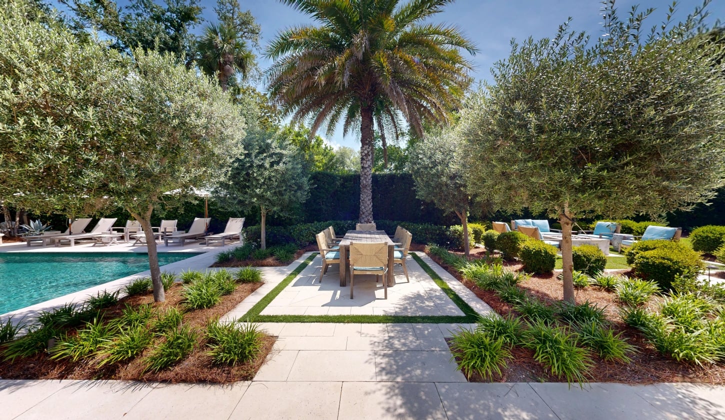 An outdoor dining table on a patio surrounded by greenery