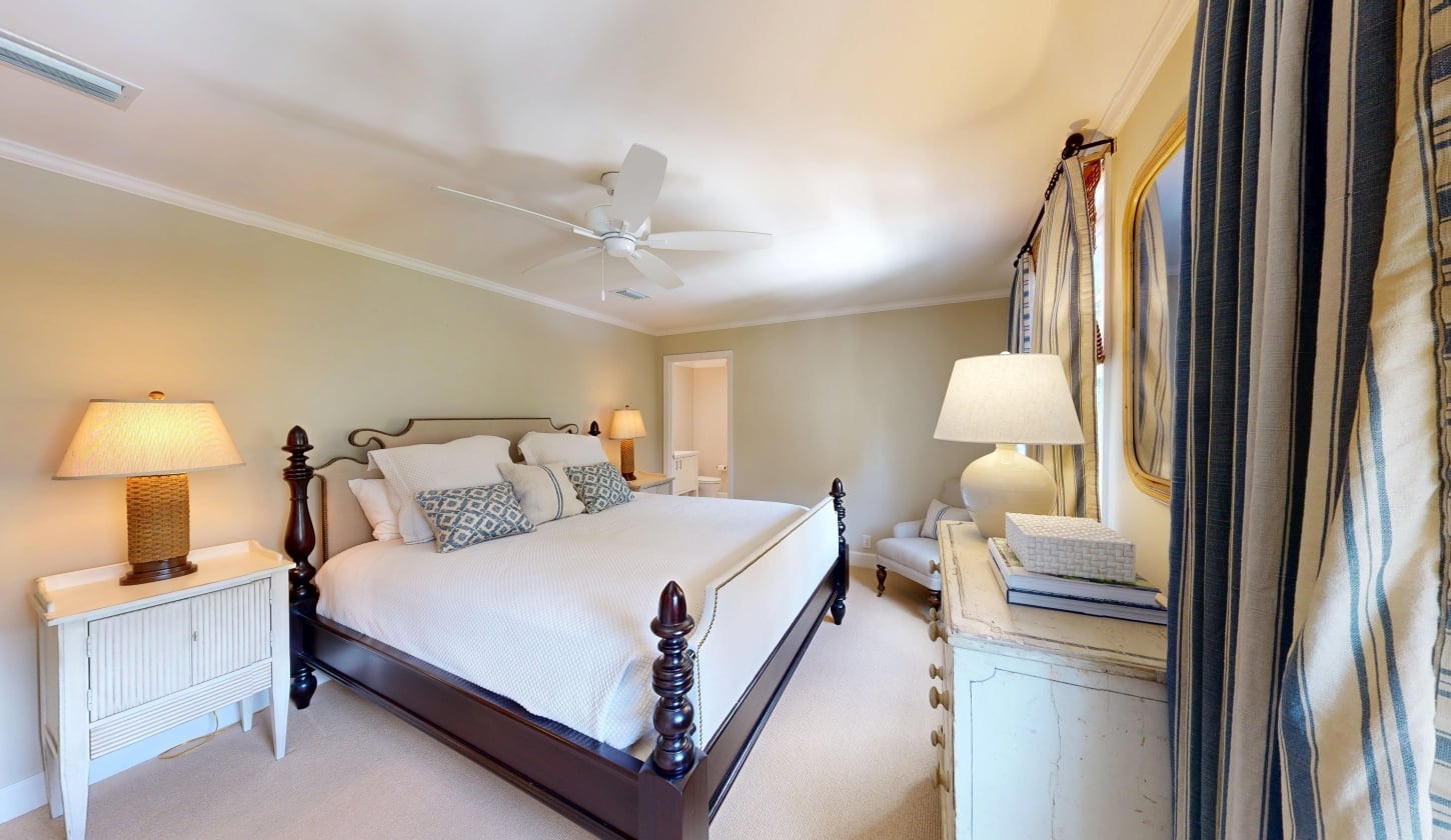 A king bed with a ceiling fam and a dresser